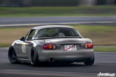 a silver sports car driving on a race track