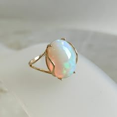 This stunning ring is set in 14k Solid Yellow Gold with Natural Ethiopion Opal with utmost precision. It is an unique statement gemstone ring for nearly every occasion and is completely hassle-free jewelry. ITEM DETAILS * GEM: Opal * GEM SIZE: 12X16mm * GEM SHAPE: Oval * GEM WEIGHT: 5.80 carats * Gold Purity: 14KT * Gold Weight: 1.64 gram * Total Weight of the Ring: 2.80 gram The Gold purity is guaranteed and it comes with authentic 14KT gold hallmark. Since my items are handmade, they are absol Real Opal Ring, Dainty Opal Ring, Opal Stone Ring, Natural Opal Ring, Precious Stones Rings, Handmade Jewelry Box, Ethiopian Opal Ring, Ring Opal, Opal Ring Gold