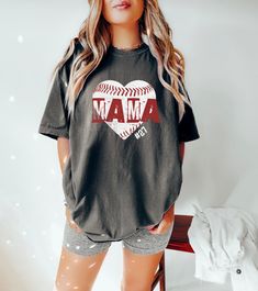 Step up to the plate in style with our 'Baseball Mom Shirt'! Designed for the trendy and proud baseball mama, this cute and fashionable tee is the perfect outfit for game day. Whether you're cheering from the bleachers or supporting your little leaguer from the sidelines, our shirt lets you do it with flair. Crafted with comfort in mind, our tee features a stylish design that's perfect for any sports-loving mom. You can show off your team spirit with your child's jersey number prominently displayed, making it a personalized top that's as unique as your little player. This Game Day Shirt for Women is more than just apparel; it's a way to celebrate your child's passion for baseball. It's ideal for little league games, school sports events, or simply showing your support during practice sessi Casual Baseball Jersey For Fans, Cotton Baseball Jersey With Short Sleeves For Fans, Cotton Short Sleeve Baseball Jersey For Fans, Game Day Baseball Season Tops With Team Name, Short Sleeve Baseball Jersey With Letter Print, Casual Pre-shrunk Baseball Jersey For Fans, Sports Fan Top With Team Name For Baseball Season, School Spirit Baseball Jersey For Baseball Season, Cotton Sports Fan Baseball Jersey With Graphic Print