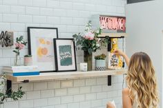 a woman sitting at a table with flowers and pictures on the wall above her head