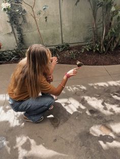 a woman kneeling down to pet a small bird