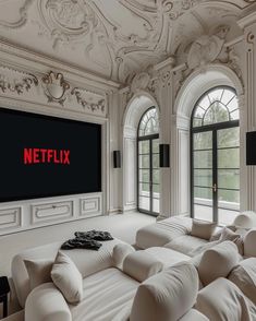 a large white couch sitting in front of a tv mounted to the side of a wall