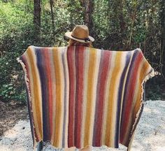 a person wearing a hat and holding a blanket in front of them with trees in the background