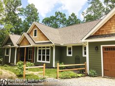 a green house with two garages in the front yard