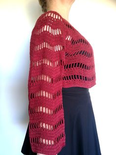 a woman is wearing a red crocheted shawl