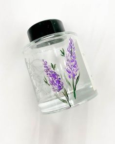 a glass jar with purple flowers painted on it