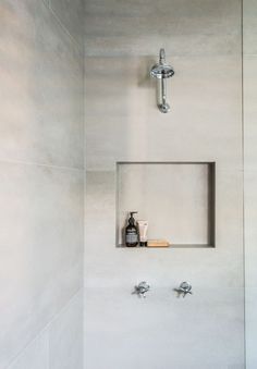 a bathroom with a shower head, soap dispenser and two faucets