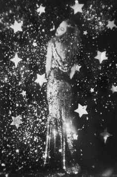 a black and white photo of a woman standing in front of stars