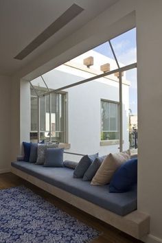 a blue couch sitting under a window next to a rug