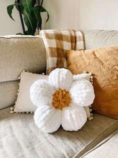 a crocheted flower sitting on top of a couch next to two throw pillows