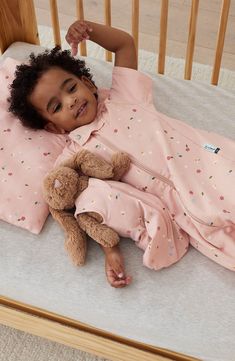 a small child laying in a crib with a teddy bear