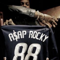 a man holding up a jersey that says asap rocky