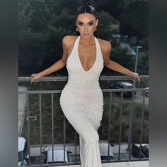 a woman in a white dress posing on a balcony