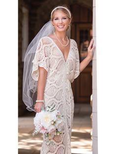 a woman in a wedding dress holding a bouquet and posing for the camera with her veil over her head