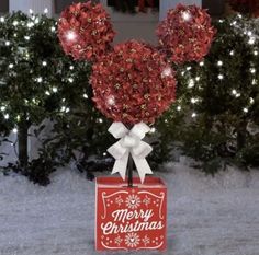 a mickey mouse christmas decoration on top of a box in front of some trees with lights