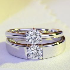 two wedding rings on top of each other, with one diamond in the middle and the other