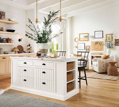 a white kitchen with wooden floors and lots of shelves on the wall next to the island