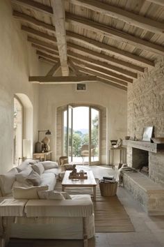 a living room filled with furniture and a fire place next to a stone wall covered in windows