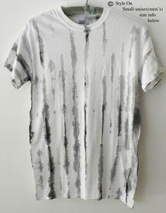 a white t - shirt hanging on a clothes hanger with black and grey stripes