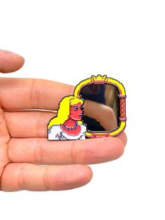 a hand holding a pin with an image of a woman's face on it