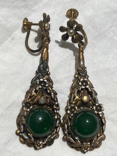 Vintage from 1940s. Beautiful ,brass plated, I believe Jade, dangle, drop, hanging, long, earrings. Has pretty floral with pearl colors on top. Great victorian style earrings. Colors are bronze, pearl, gold,  green. Look like also has swarovski gems that are little dim from age. **The green gem looks like jade, or jade glass, green glass. I DO NOT KNOW  for sure if its jade. Sold as is.   In good condition. Brass has worn off in places, white patina,  Also has patina from old age. Sold as is. ** Antique Drop Earrings With Antique Finish, Antique Style Drop Earrings With Antique Finish, Antique Dangle Earrings, Green Vintage Charm Brass Jewelry, Victorian Drop Earrings With Antique Finish, Green Brass Jewelry With Vintage Charm, Antique Bronze Drop Earrings, Victorian Antique Finish Drop Earrings, Vintage Green Evening Jewelry