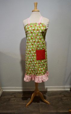 a green and pink apron on a mannequin with polka dot print, ruffle trim