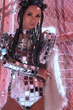 a woman in a bodysuit with feathers on her head and hands behind her back