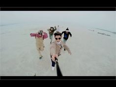 a group of people standing on top of a beach next to each other in the sand