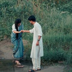 two people standing next to each other near water