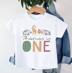 Personalised First Birthday Safari T-shirt T-shirt is 100% cotton.  We design & print our products with care & love! We use the best quality vinyls, inks & transfers on all products. * * * * * * * * * * * * * * * * * * * * * * * * * * * * * CARE INSTRUCTIONS: Wash inside out on gentle wash, Do not tumble dry. * * * * * * * * * * * * * * * * * * * * * * * * * * * * * SHIPPING: We want to get your product to you as quickly as possible, your purchase will be shipped through Australia post, Express post is available for selection. * * * * * * * * * * * * * * * * * * * * * * * * * * * * * GUARANTEE: We stand behind our products with a 100% guarantee; if you are unsatisfied with our product, please let us know & we will rectify any issues. We are unable to refund products due to change of mind o Cotton Crew Neck T-shirt For Birthday Gift, First Birthday Graphic Tee With Crew Neck, Birthday T-shirt With Name Print, Short Sleeve, Birthday Name Print Short Sleeve T-shirt, Character Print Short Sleeve T-shirt For Birthday Gift, Cotton T-shirt With Character Print For Birthday Gift, White Character Print Top For Birthday Gift, Character Print Short Sleeve T-shirt For Birthday, Cotton Graphic Print T-shirt For Birthday