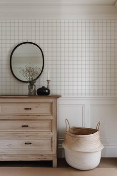 a dresser with a mirror and vase on top of it next to a wooden chest