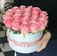 a person holding a blue box with pink roses in it