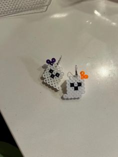 two small white and orange earrings on top of a table next to a computer keyboard