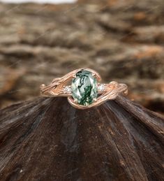 a ring with a green and white stone in the center on top of a rock