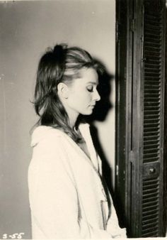 a black and white photo of a woman leaning against a wall with her eyes closed