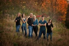 a group of people standing next to each other on a field with trees in the background