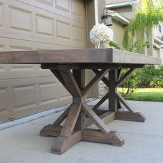 a wooden table sitting on top of a cement floor next to a garage door in front of a house