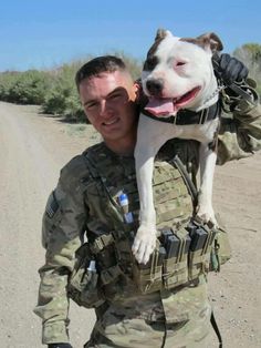 a man in camouflage carrying a dog on his back