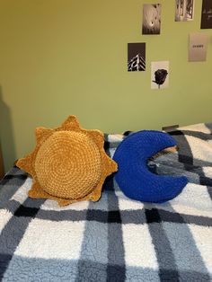 a bed with blue and yellow pillows on top of it next to a sun shaped pillow