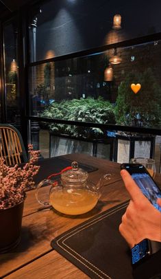 a person sitting at a table with a cell phone in front of them and plants