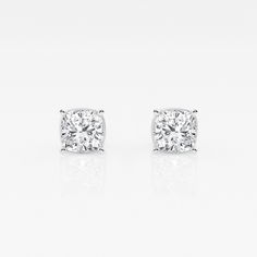 a pair of diamond stud earrings on a white background with reflection in the middle,