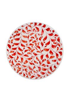 a red and white plate with leaves on it's surface, against a white background