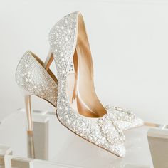 a pair of high heeled shoes with pearls on them sitting on top of a table