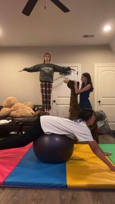 two people standing on top of a ball in a room