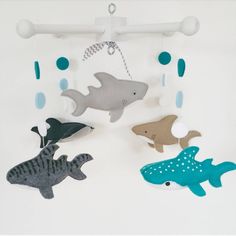 three felt sea animals hanging from hooks on a white wall with blue and gray circles