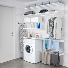 a washer and dryer in a room with white tile walls, open shelving