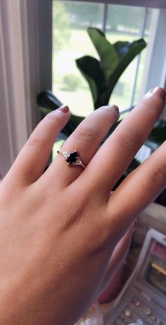 a woman's hand with a diamond ring on her finger, next to a window