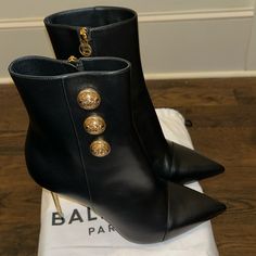 Balmain "Roni" Smooth Calfskin Leather Booties. 4" Metallic Stiletto Heel. Pointed Cap Toe. Golden Logo Button Detailing. Side Zip Eases Dress. Calfskin Leather Lining. Smooth Sole. Made In Italy. New Dustbag Only No Box Luxury Ankle Boots With 4-inch Heel, Party Heels With Gold-tone Hardware, Designer Calf Leather Heels With Gold-tone Hardware, Luxury Heeled Boots With Leather Lining For Party, Evening Heels In Leather With Gold-tone Hardware, Evening Heels With Gold-tone Hardware In Leather, Luxury Boots With 4-inch Heel For Night Out, Luxury Ankle Boots With Sculpted Heel, Luxury Boots With Pointed Toe And Reinforced Heel