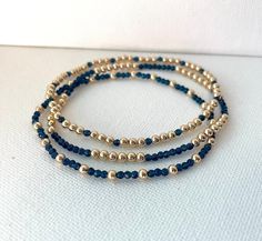 These beautiful bracelets are made of 14k gold filled beads and navy blue beads which come on a stretch cord to easily put on and take off. They're elegant, perfect for every occasion and make great gifts!  Patterns may vary slightly depending on wrist size. Gold filled beads size: 3MM Navy blue beads size: 2.5MM *FREE SHIPPING* Diy Elegant Bracelet, Navy Blue Bracelets, Navy Blue And Gold Jewelry, Blue And Gold Beaded Bracelets, Navy Blue Beaded Bracelet, Navy Blue Bracelet, Navy Jewelry, Homemade Bracelets, Blue Beaded Bracelets