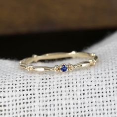 a yellow gold ring with blue sapphire stones on the inside, sitting on top of a white cloth